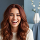 A happy woman with vibrant, healthy hair smiles genuinely at the camera.